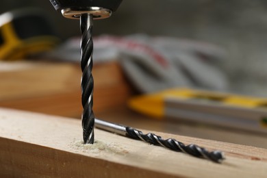 Photo of Drilling hole in wooden plank on table, closeup