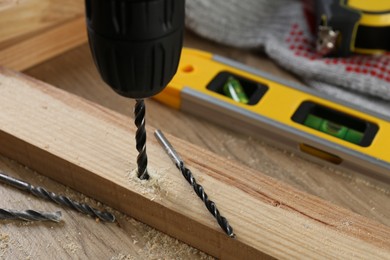 Photo of Drilling hole in plank on wooden table, closeup