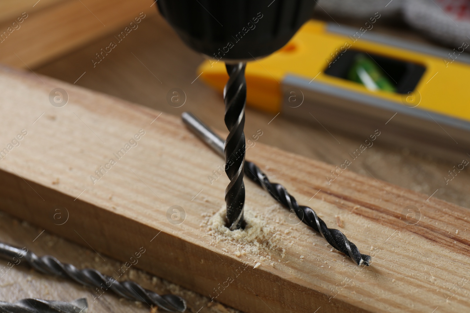 Photo of Drilling hole in plank on wooden table, closeup