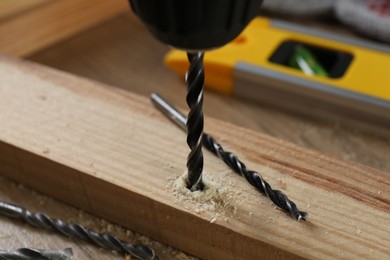 Drilling hole in plank on wooden table, closeup