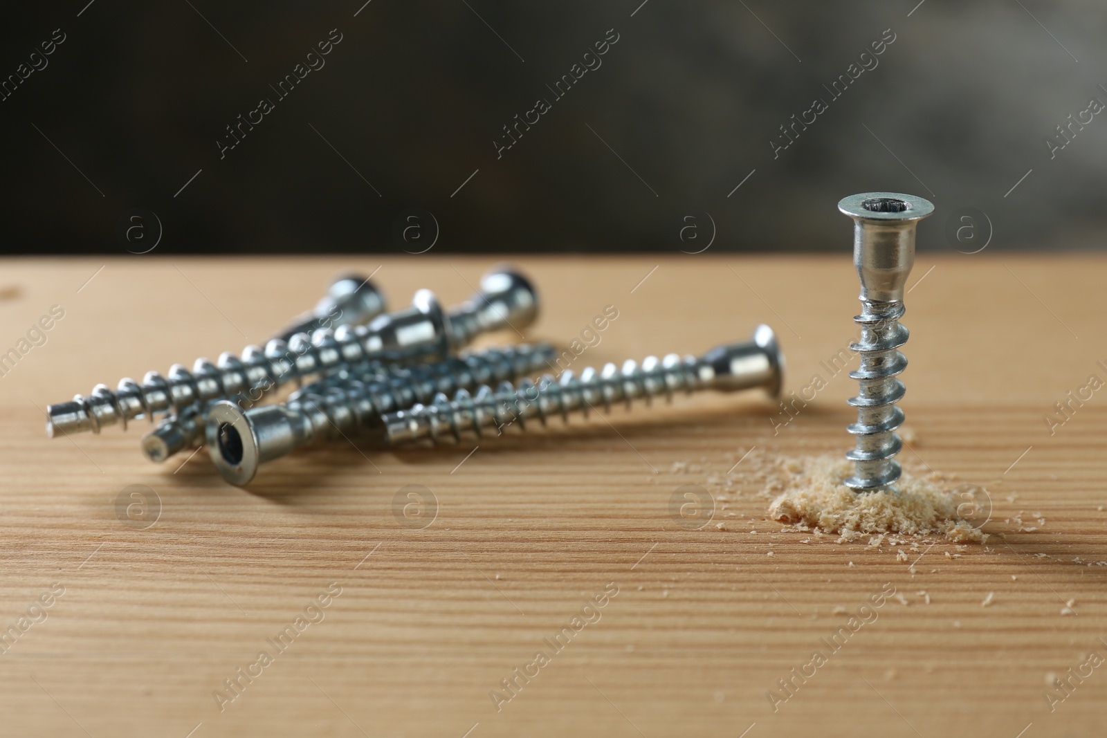 Photo of Many screws and wooden plank against gray background, closeup