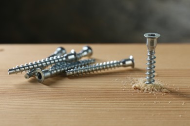 Many screws and wooden plank against gray background, closeup