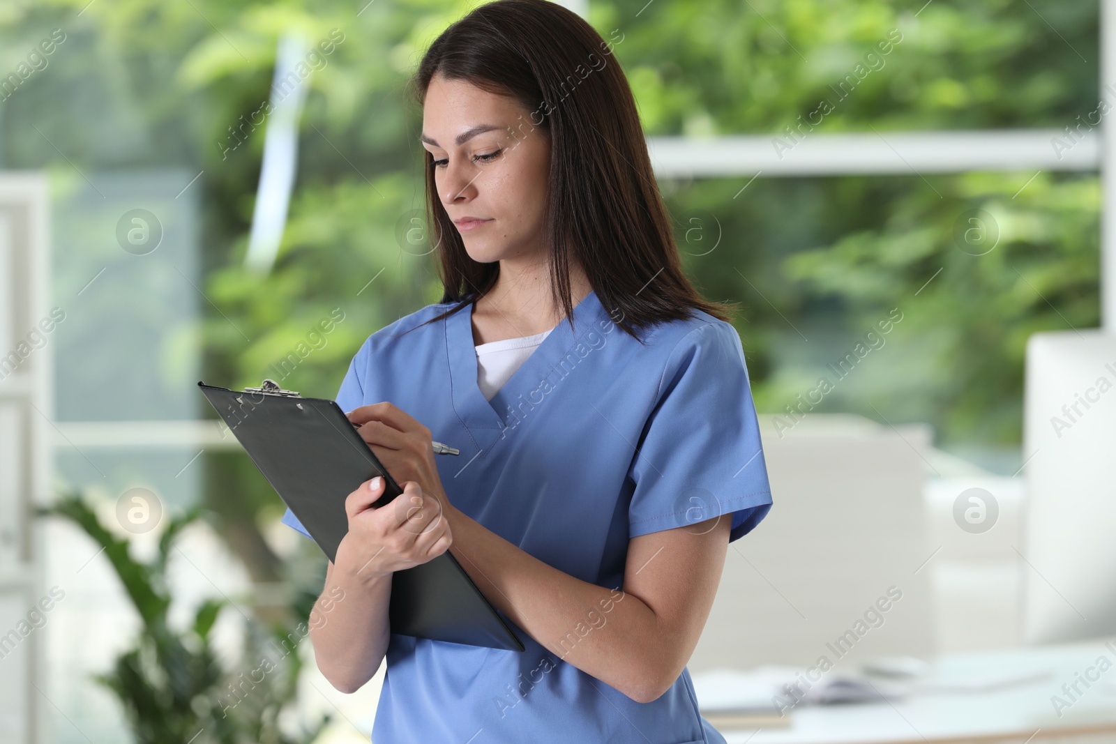 Photo of Beautiful nurse working with clipboard in hospital office