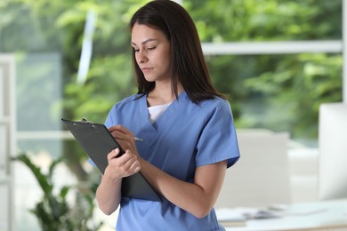Photo of Beautiful nurse working with clipboard in hospital office
