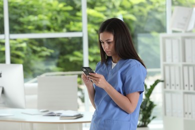 Photo of Beautiful nurse with smartphone in hospital office