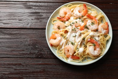 Photo of Delicious pasta with shrimps and creamy sauce on wooden table, top view. Space for text