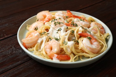 Photo of Delicious pasta with shrimps and creamy sauce on wooden table, closeup