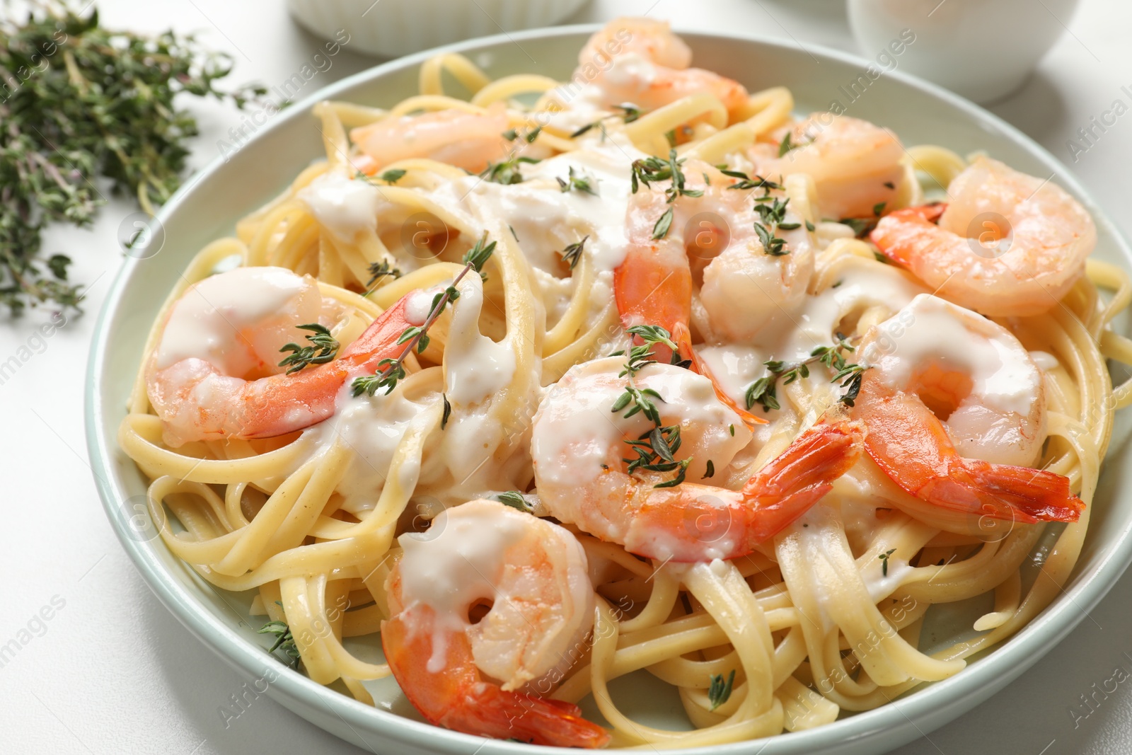 Photo of Delicious pasta with shrimps and creamy sauce on white table, closeup