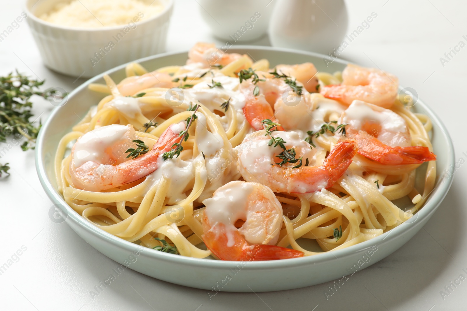 Photo of Delicious pasta with shrimps and creamy sauce on white table, closeup