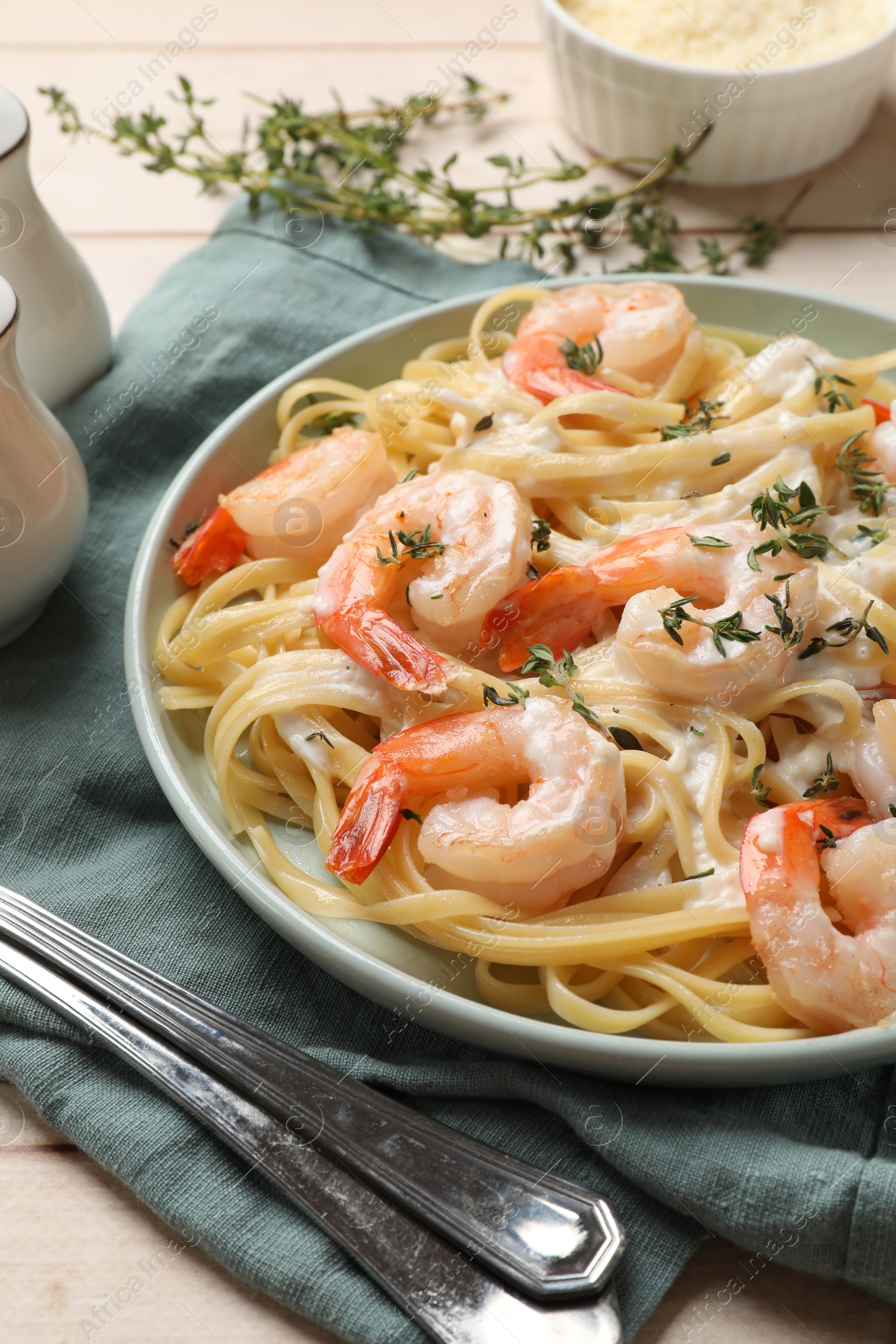 Photo of Delicious pasta with shrimps and creamy sauce served on wooden table, closeup