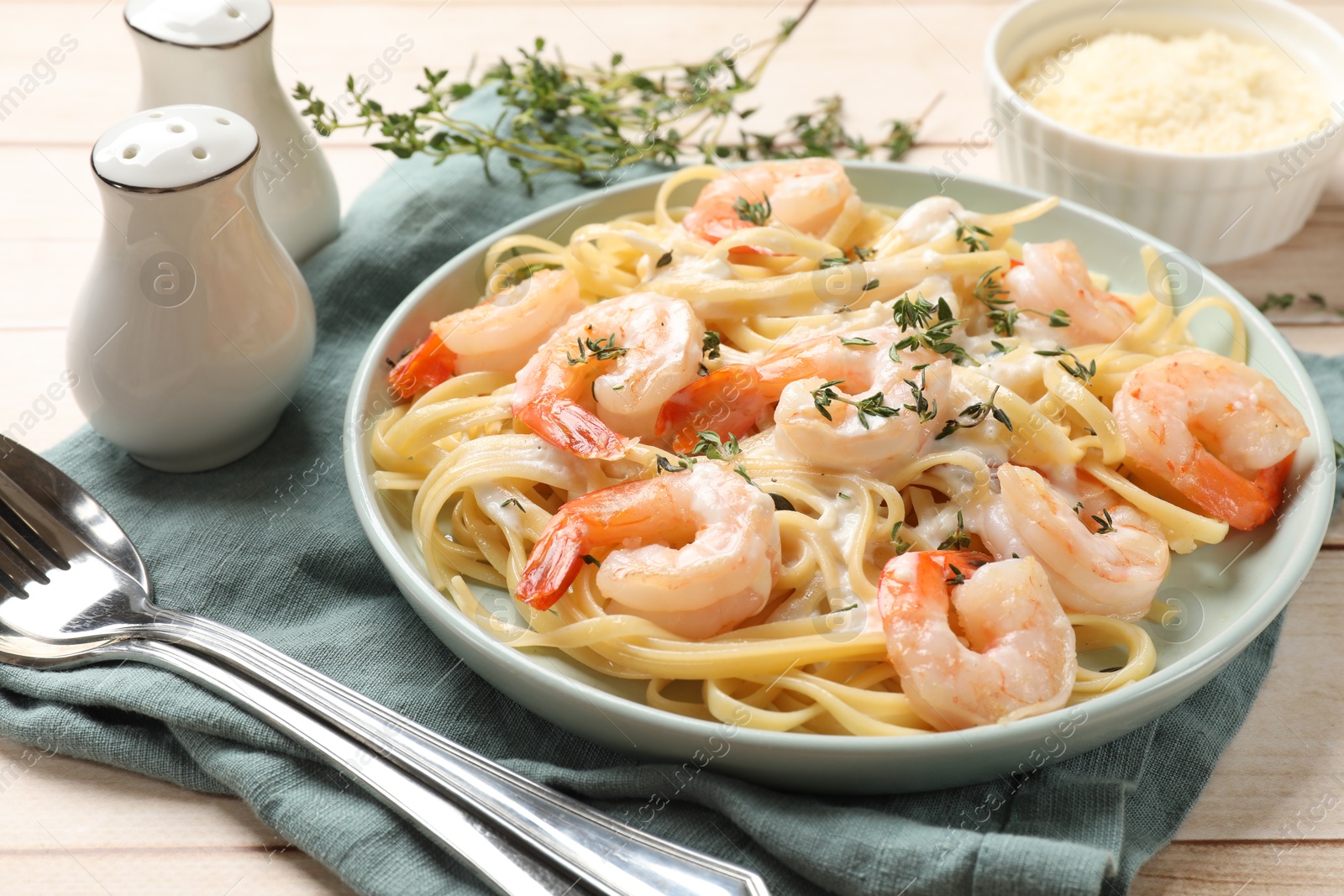 Photo of Delicious pasta with shrimps and creamy sauce served on wooden table, closeup