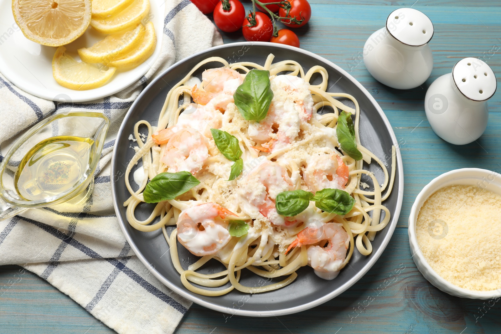 Photo of Tasty pasta with shrimps on light blue wooden table, flat lay