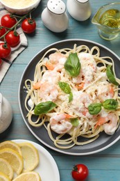 Photo of Tasty pasta with shrimps served on light blue wooden table, flat lay