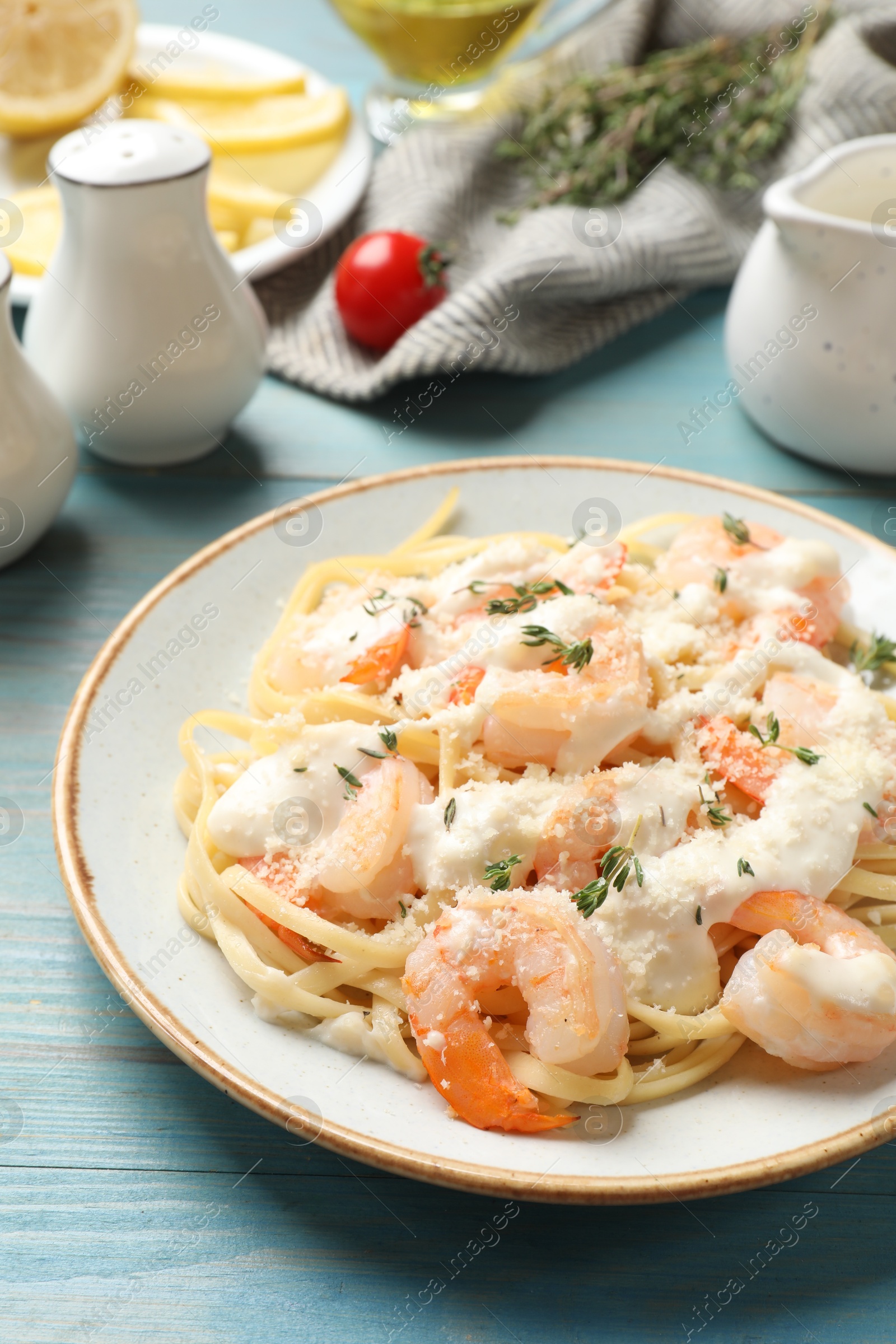 Photo of Tasty pasta with shrimps, creamy sauce and cheese on light blue wooden table, closeup