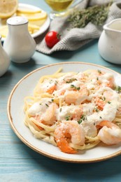 Photo of Tasty pasta with shrimps, creamy sauce and cheese on light blue wooden table, closeup