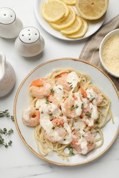 Photo of Tasty pasta with shrimps, creamy sauce and cheese served on white table, flat lay