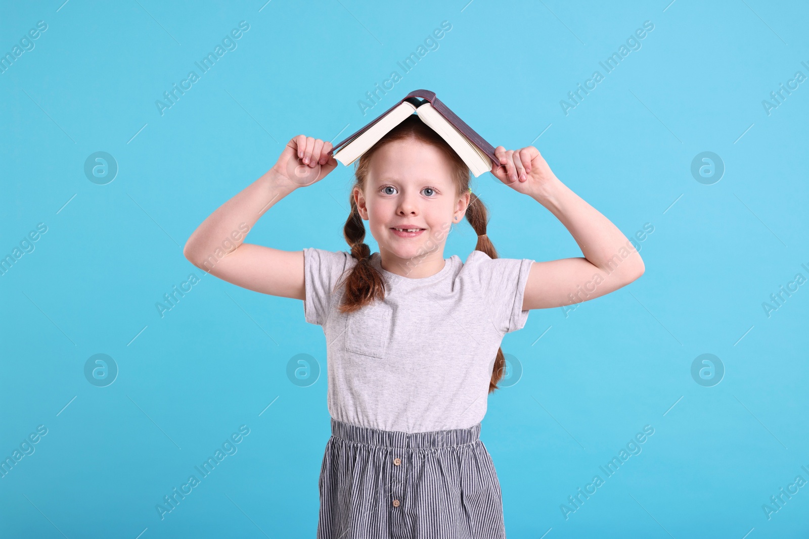 Photo of Smiling girl with book on light blue background