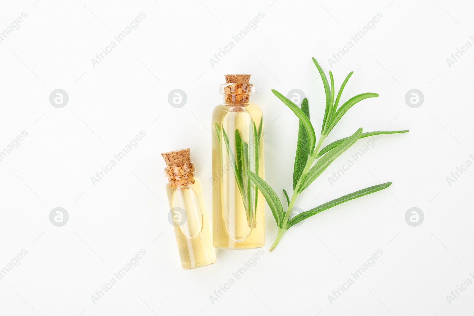 Photo of Aromatic essential oils in bottles and rosemary on white background, flat lay