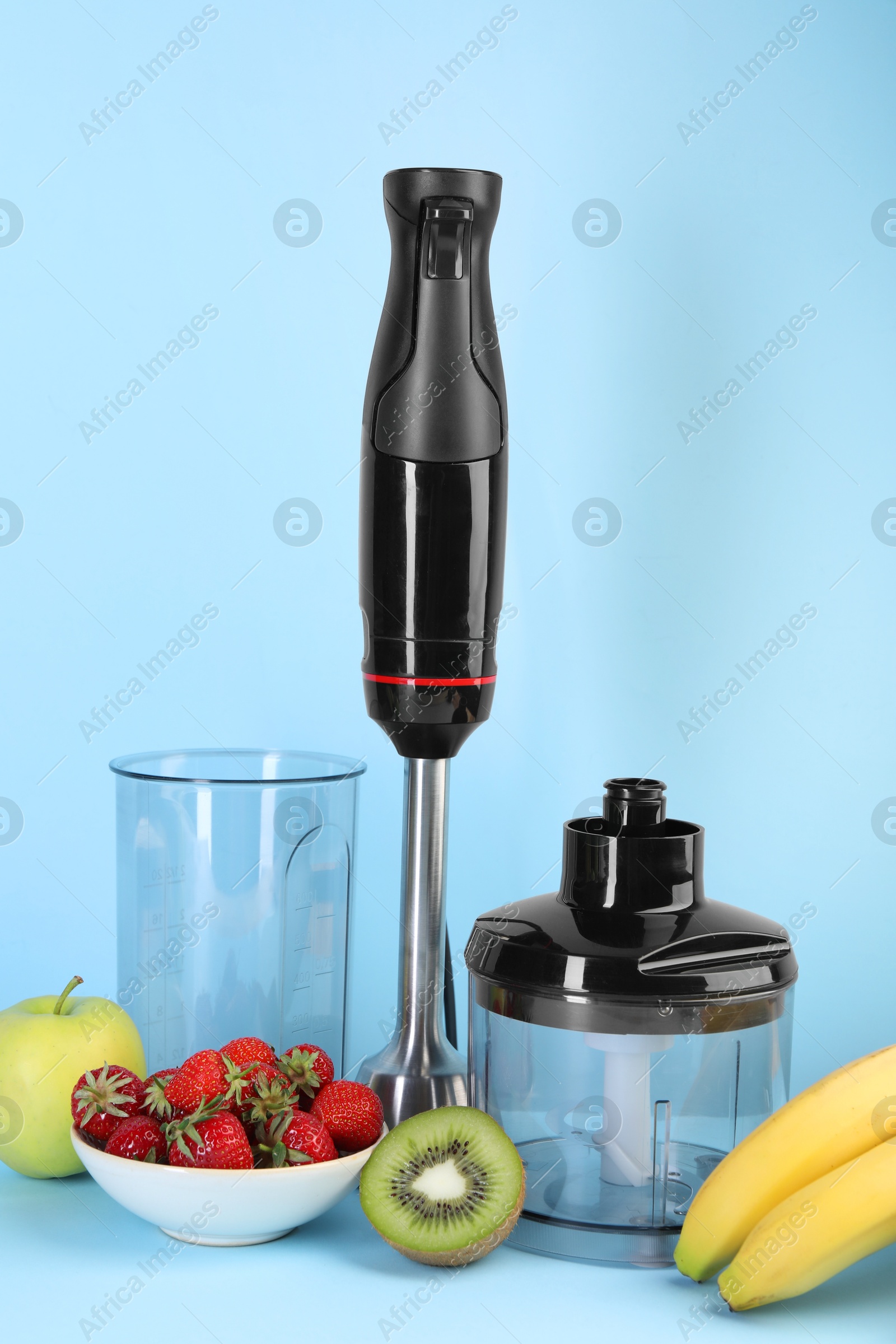 Photo of Hand blender kit, fresh fruits and strawberries on light blue background