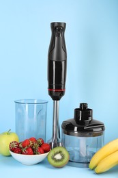 Photo of Hand blender kit, fresh fruits and strawberries on light blue background