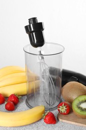 Photo of Hand blender kit, fresh fruits and strawberries on gray table against white background