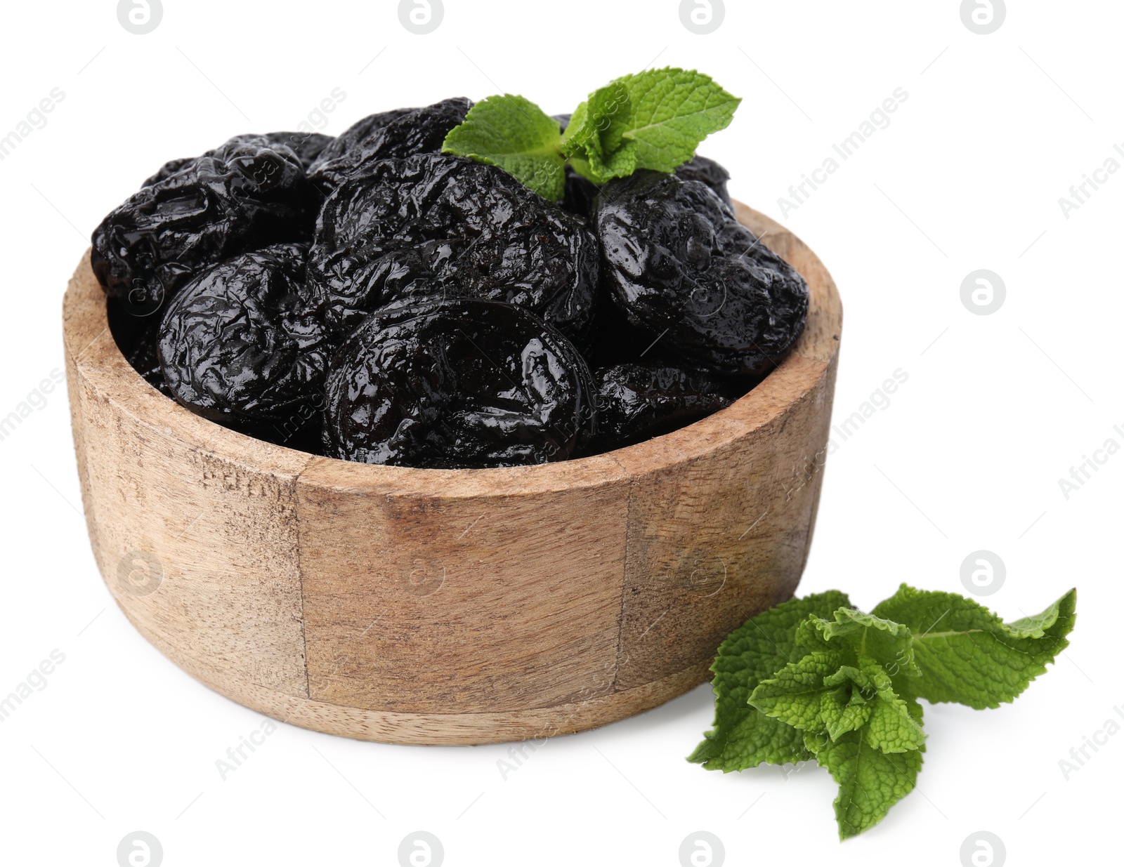 Photo of Tasty dried plums (prunes) and mint leaves in wooden bowl on white background