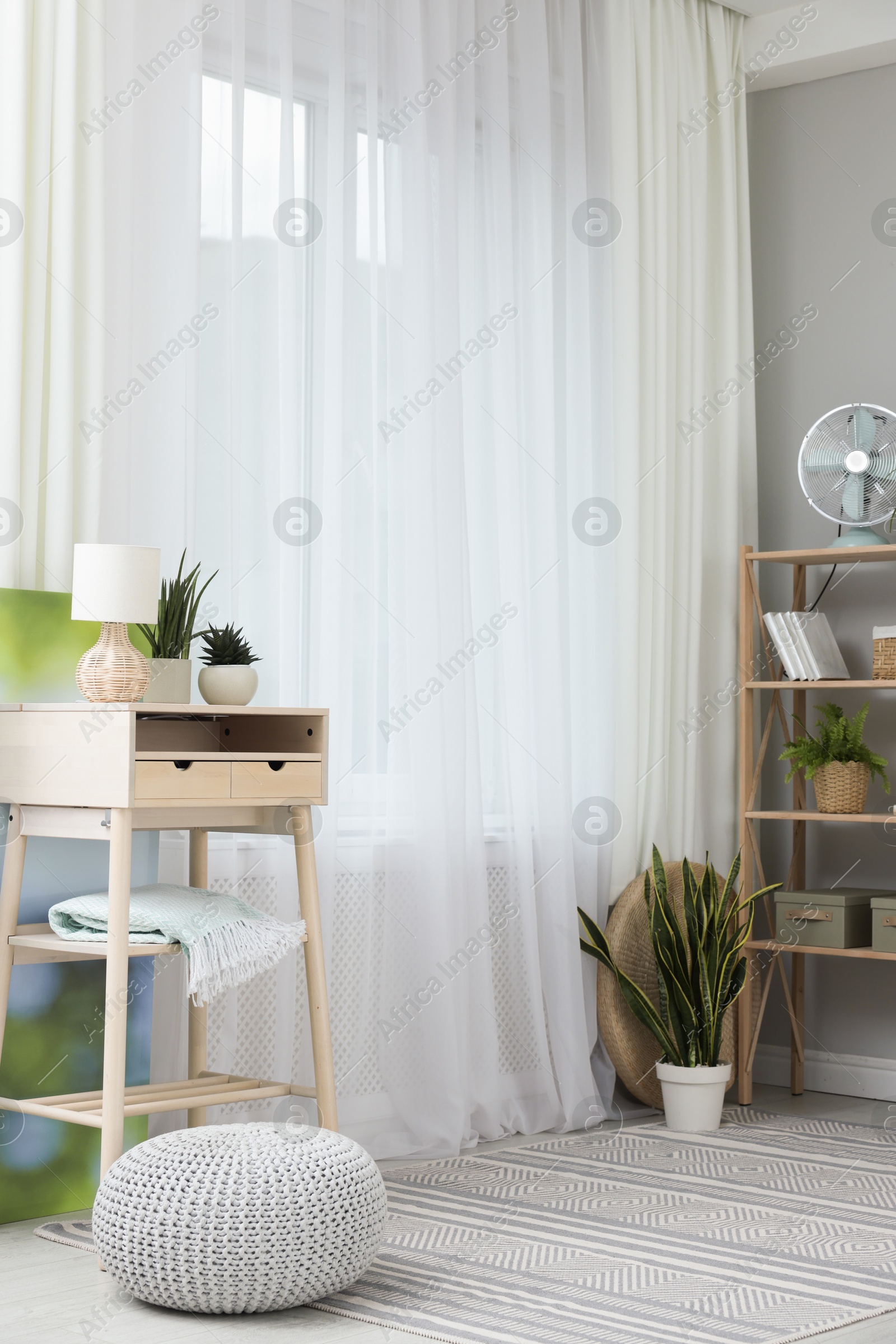 Photo of Window with beautiful curtains, pouf, houseplants and furniture in room. Interior design