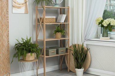 Photo of Window with beautiful curtain, shelving unit and houseplants in room. Interior design