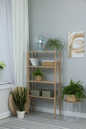 Photo of Window with beautiful curtain, shelving unit and houseplants in room. Interior design