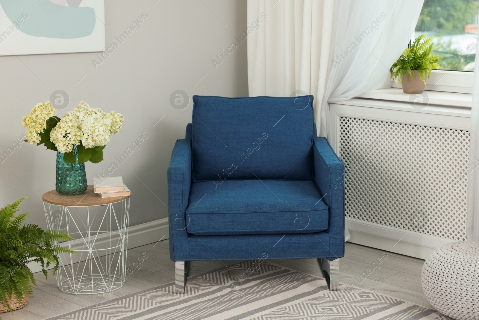 Photo of Soft armchair, side table, flowers and window with curtains in room. Interior design