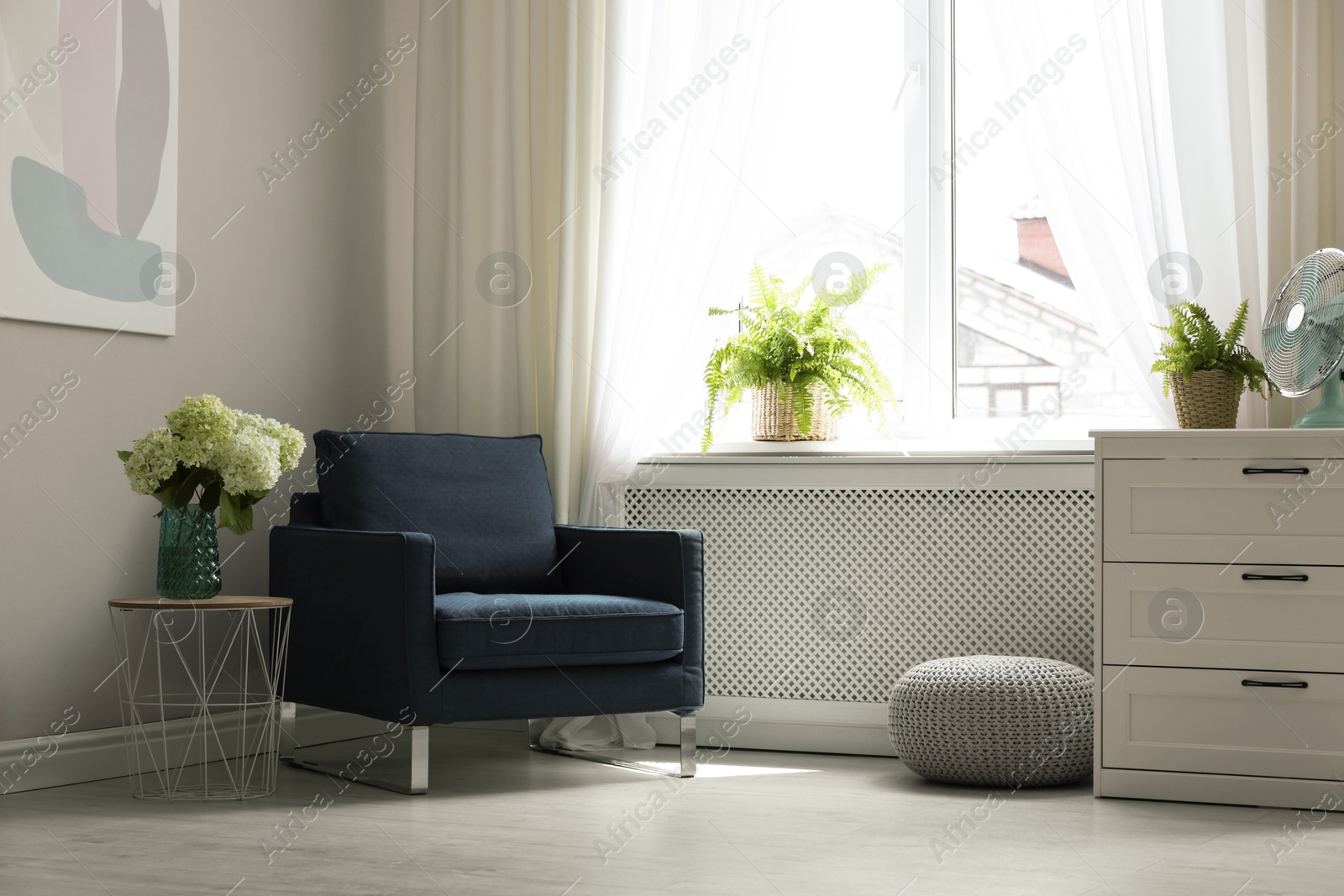 Photo of Soft armchair, side table, chest of drawers and window with curtains in room. Interior design