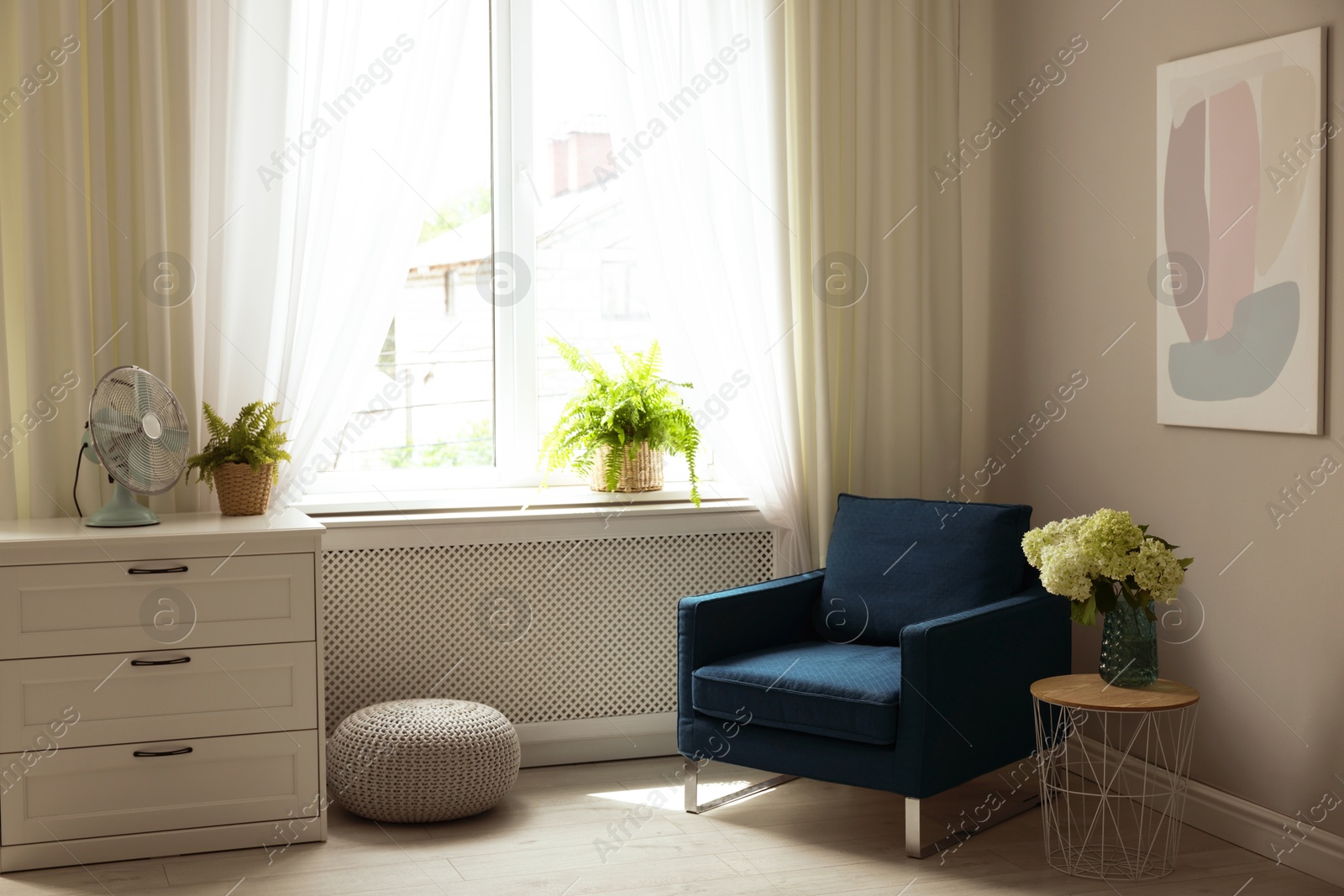 Photo of Soft armchair, side table, chest of drawers and window with curtains in room. Interior design