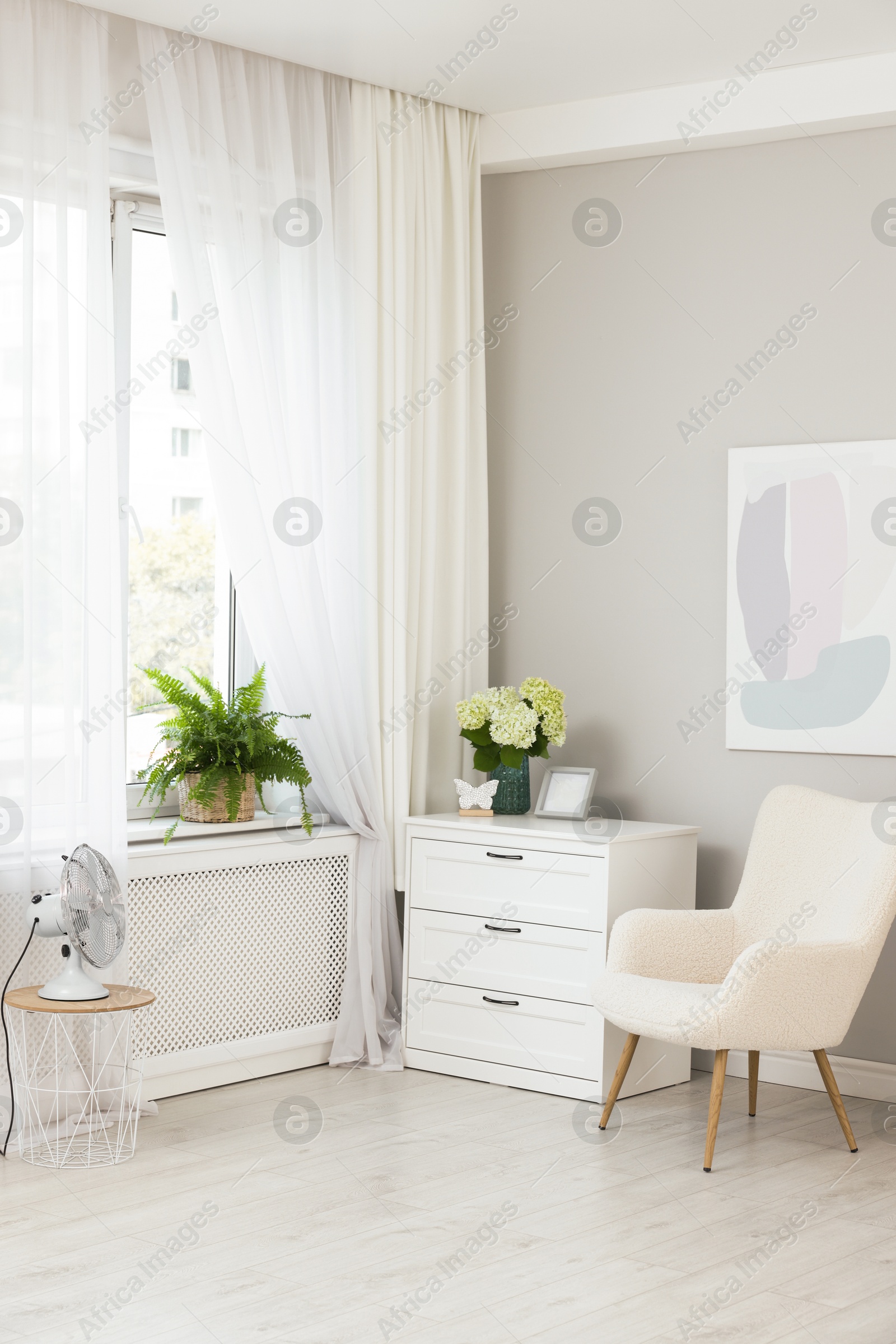 Photo of Soft armchair, chest of drawers, houseplant and window with curtains in room. Interior design