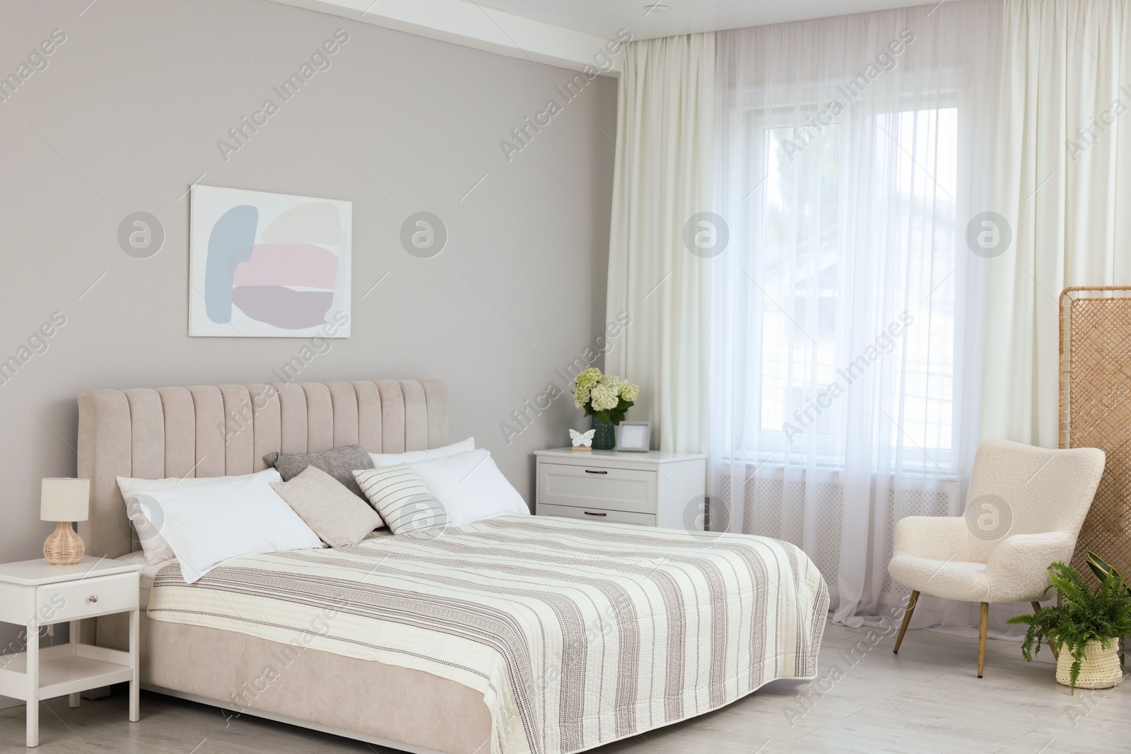 Photo of Large bed, nightstand, chest of drawers, armchair and window with curtains in bedroom. Interior design