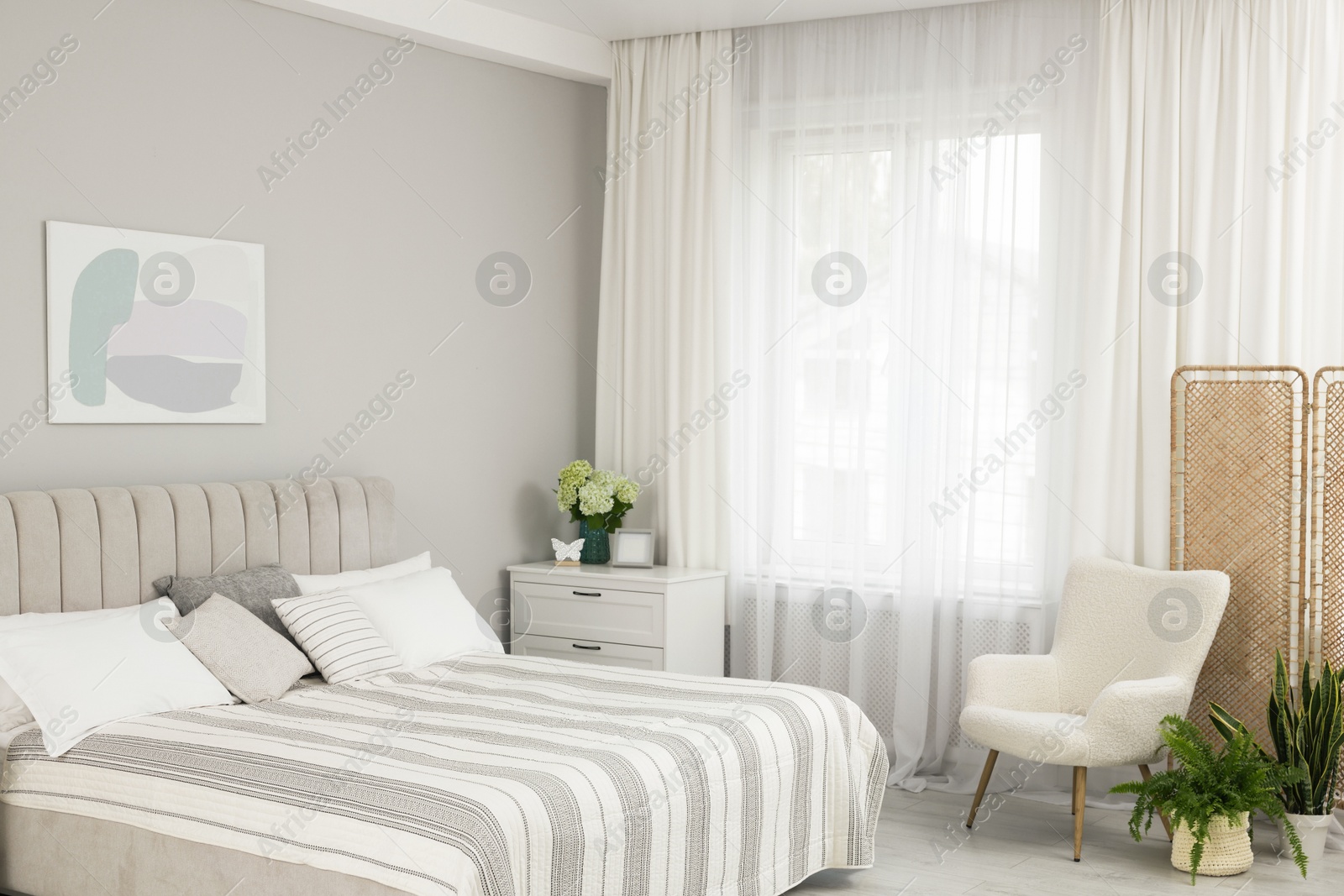 Photo of Large bed, chest of drawers, armchair and window with curtains in bedroom. Interior design