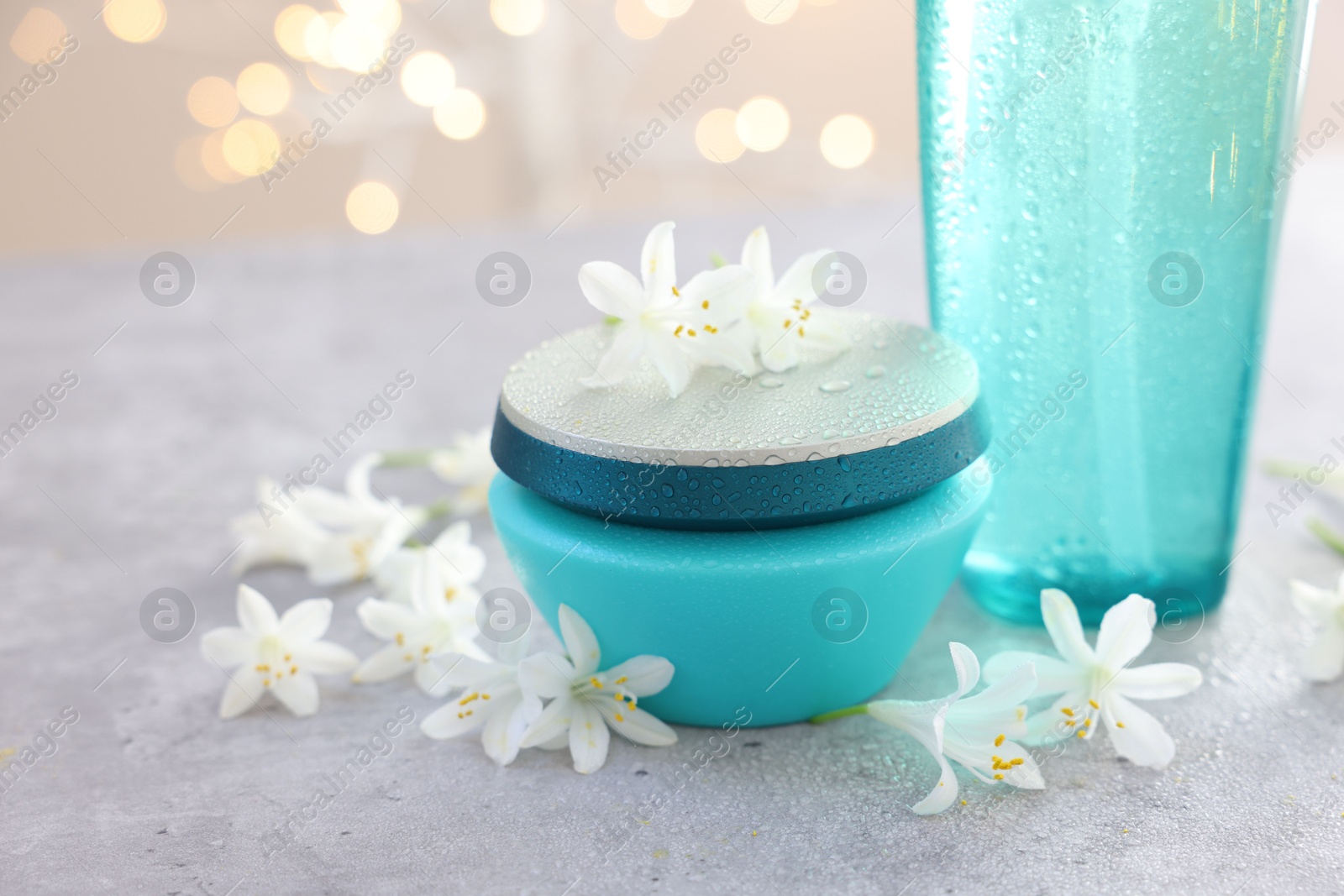 Photo of Cosmetic products and beautiful jasmine flowers on grey table, closeup