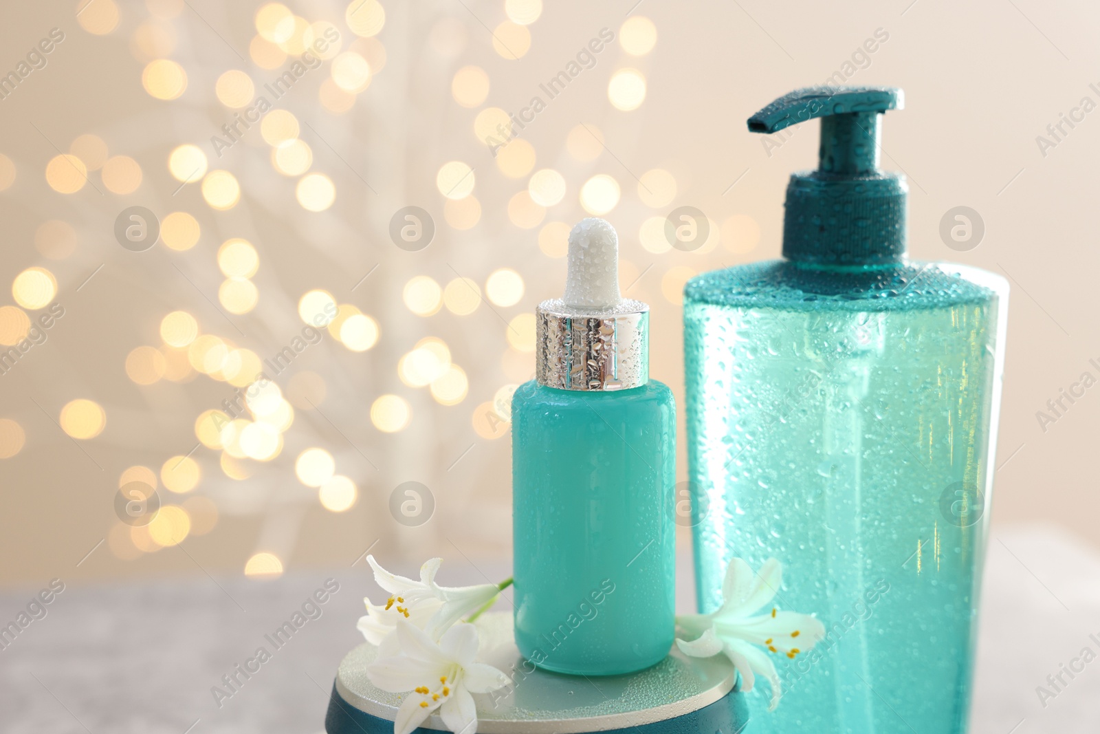 Photo of Cosmetic products and jasmine flowers against beige background with blurred lights, closeup