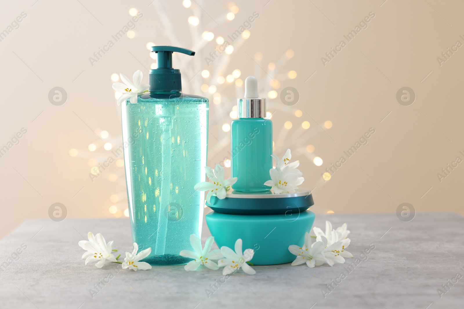 Photo of Cosmetic products and beautiful jasmine flowers on grey table