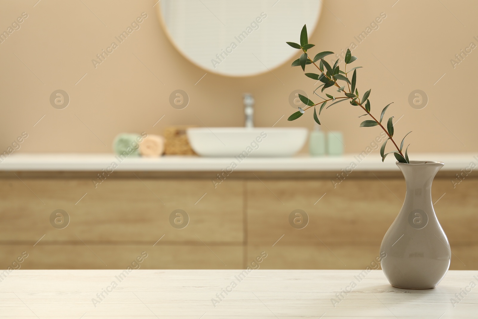 Photo of Beautiful vase with green twig on table in bathroom. Space for text