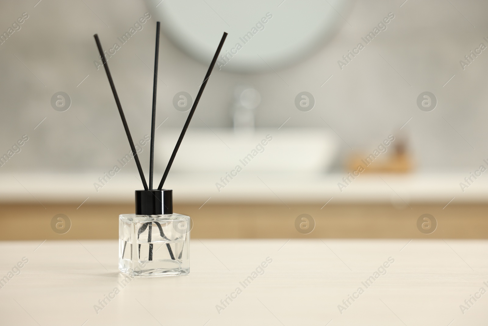 Photo of Reed diffuser on light table in bathroom, space for text