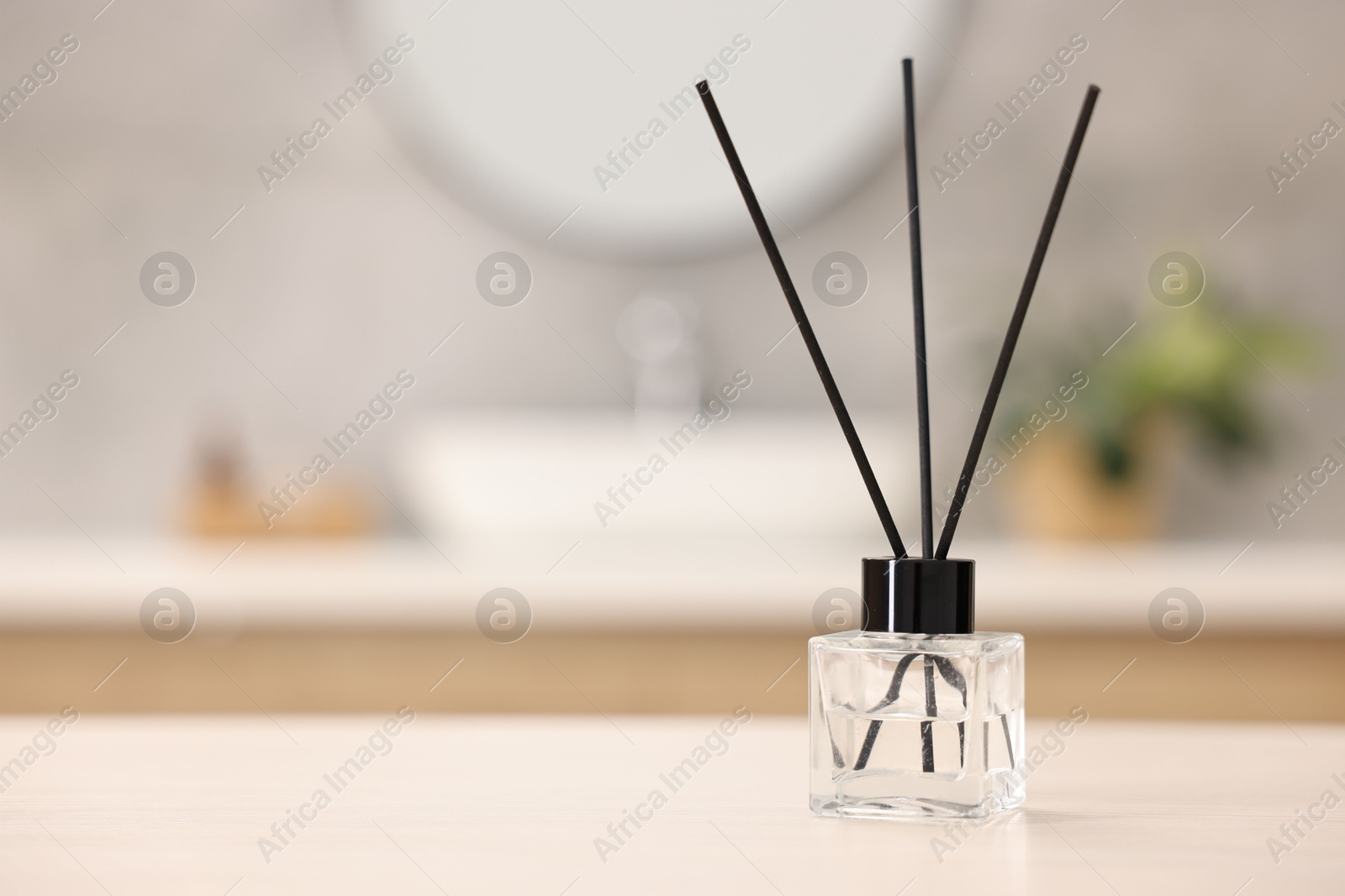 Photo of Reed diffuser on light table in bathroom, space for text