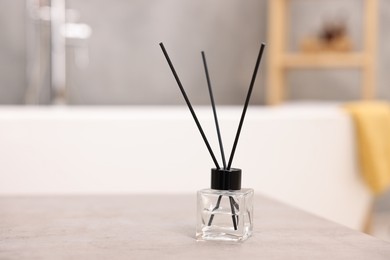 Photo of Reed diffuser on light grey table in bathroom, space for text