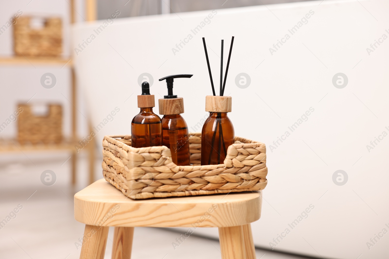 Photo of Personal care products and reed diffuser on wooden stool in bathroom