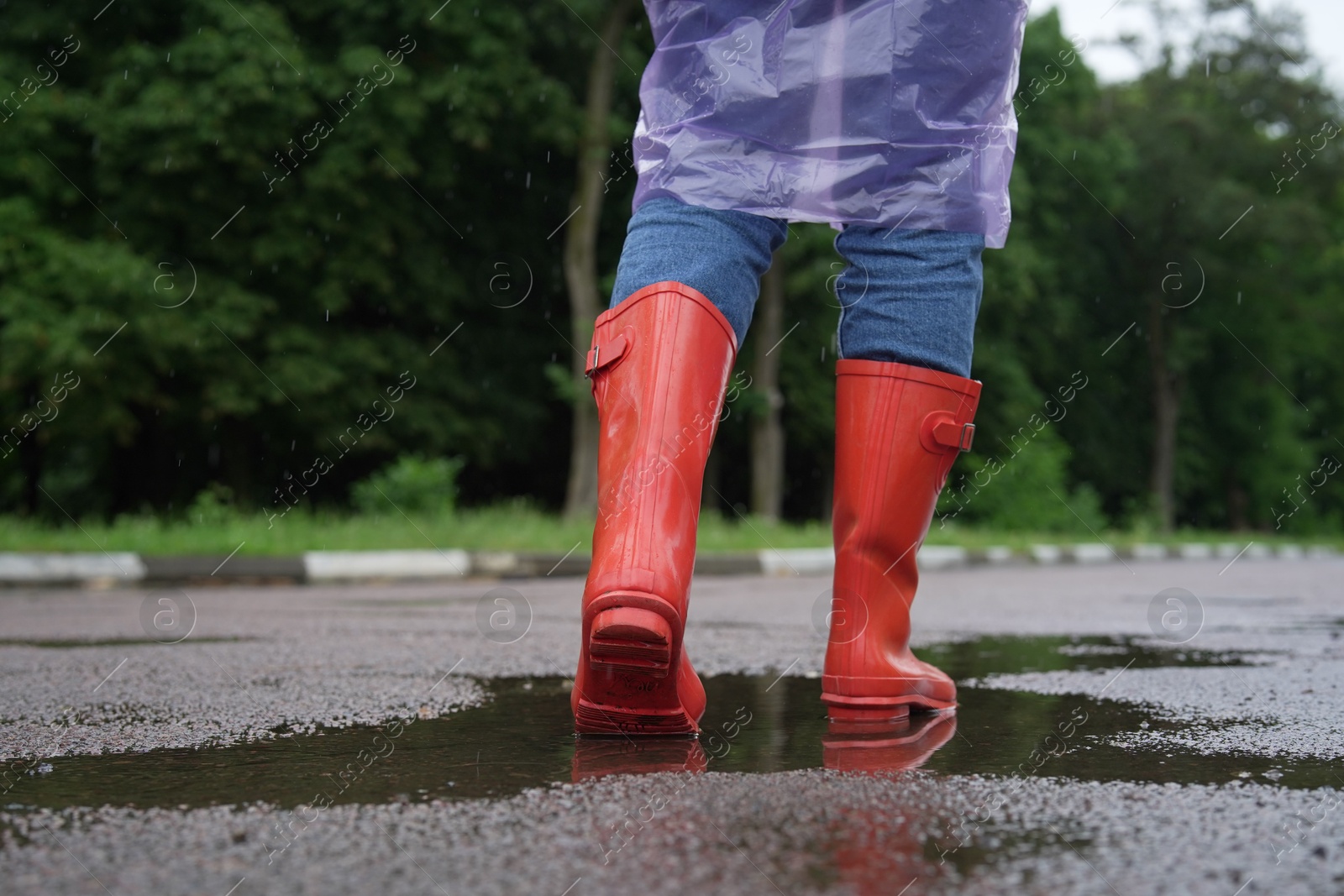 Photo of Woman in red rubber boots walking outdoors, closeup. Space for text