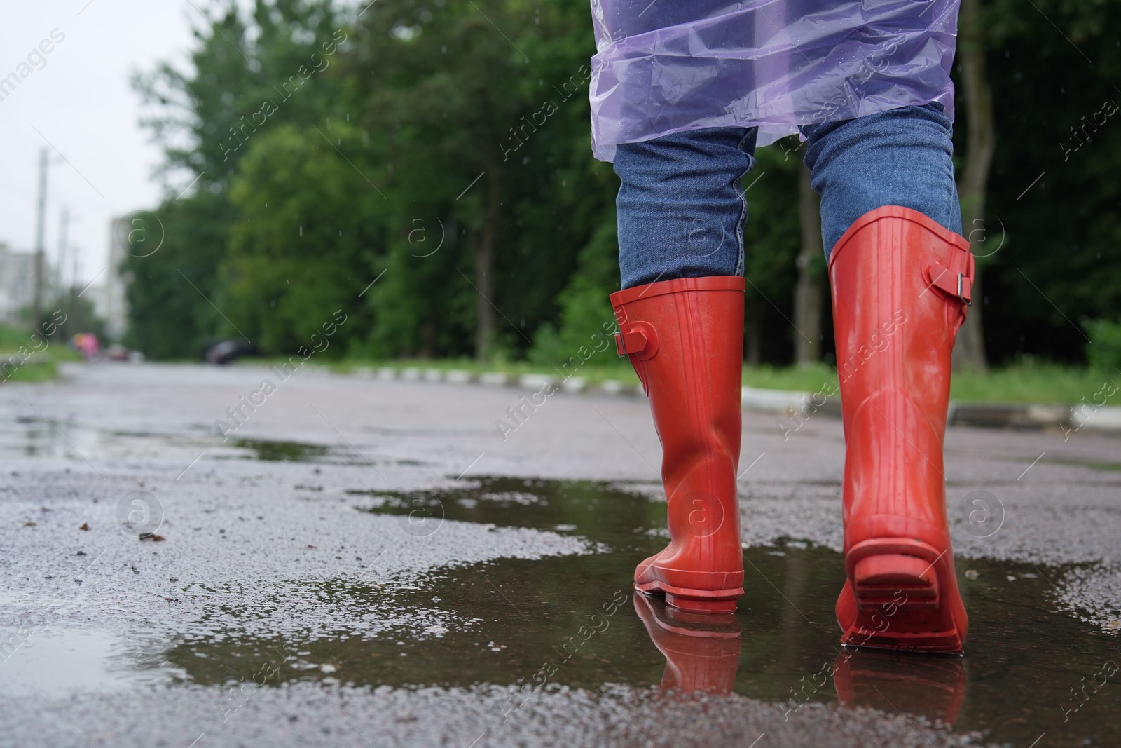 Photo of Woman in red rubber boots walking outdoors, closeup. Space for text