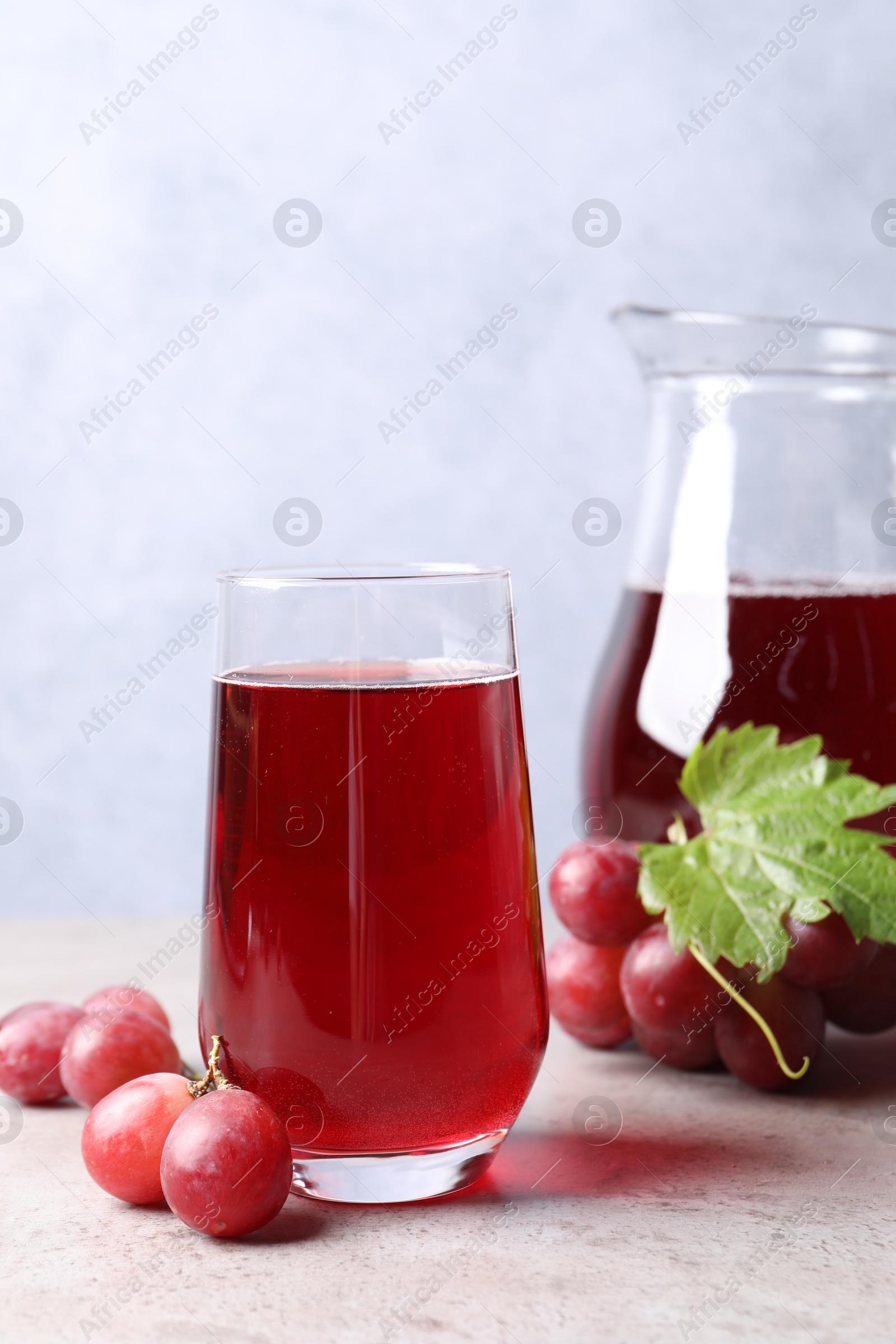 Photo of Ripe grapes and tasty juice on grey table