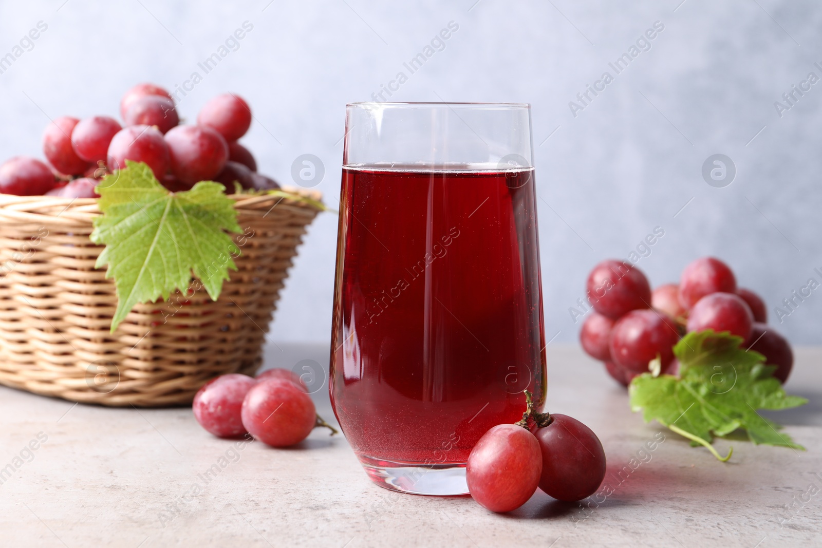 Photo of Ripe grapes and tasty juice on grey table