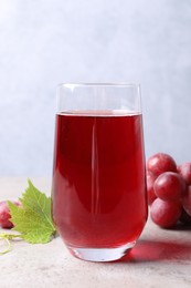 Photo of Ripe grapes and tasty juice on grey table