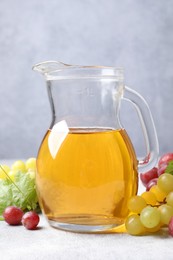 Photo of Ripe grapes and jug of tasty juice on grey table