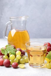 Photo of Ripe grapes and tasty juice on grey table